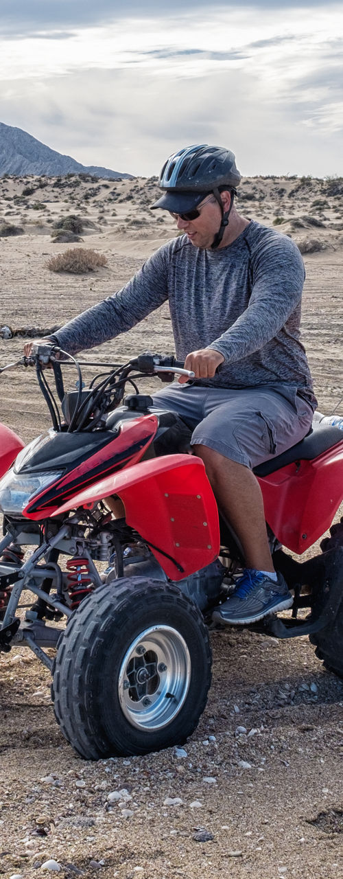 Man riding red ATV in desert landscape
