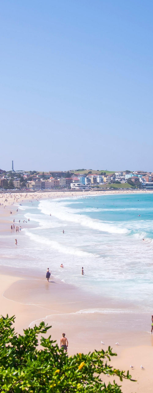 Sunny beach with waves and distant crowd