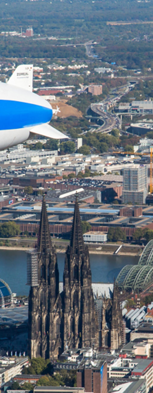 Blue and white airship over Cologne cityscape