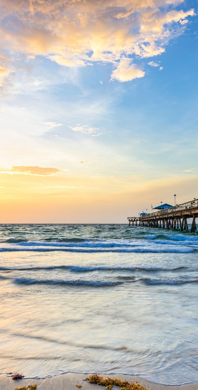 Scenic ocean pier at sunrise with seaweed