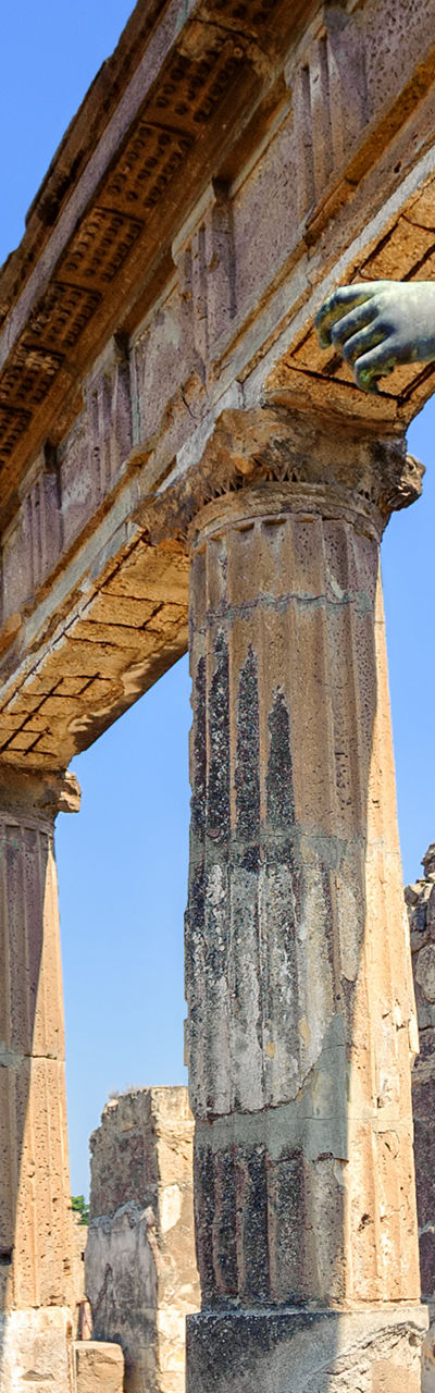 Ancient statue in Pompeii ruins under blue sky