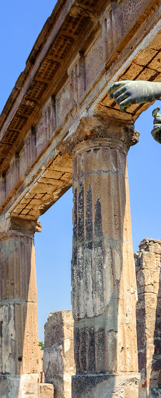 Ancient statue in Pompeii ruins under blue sky