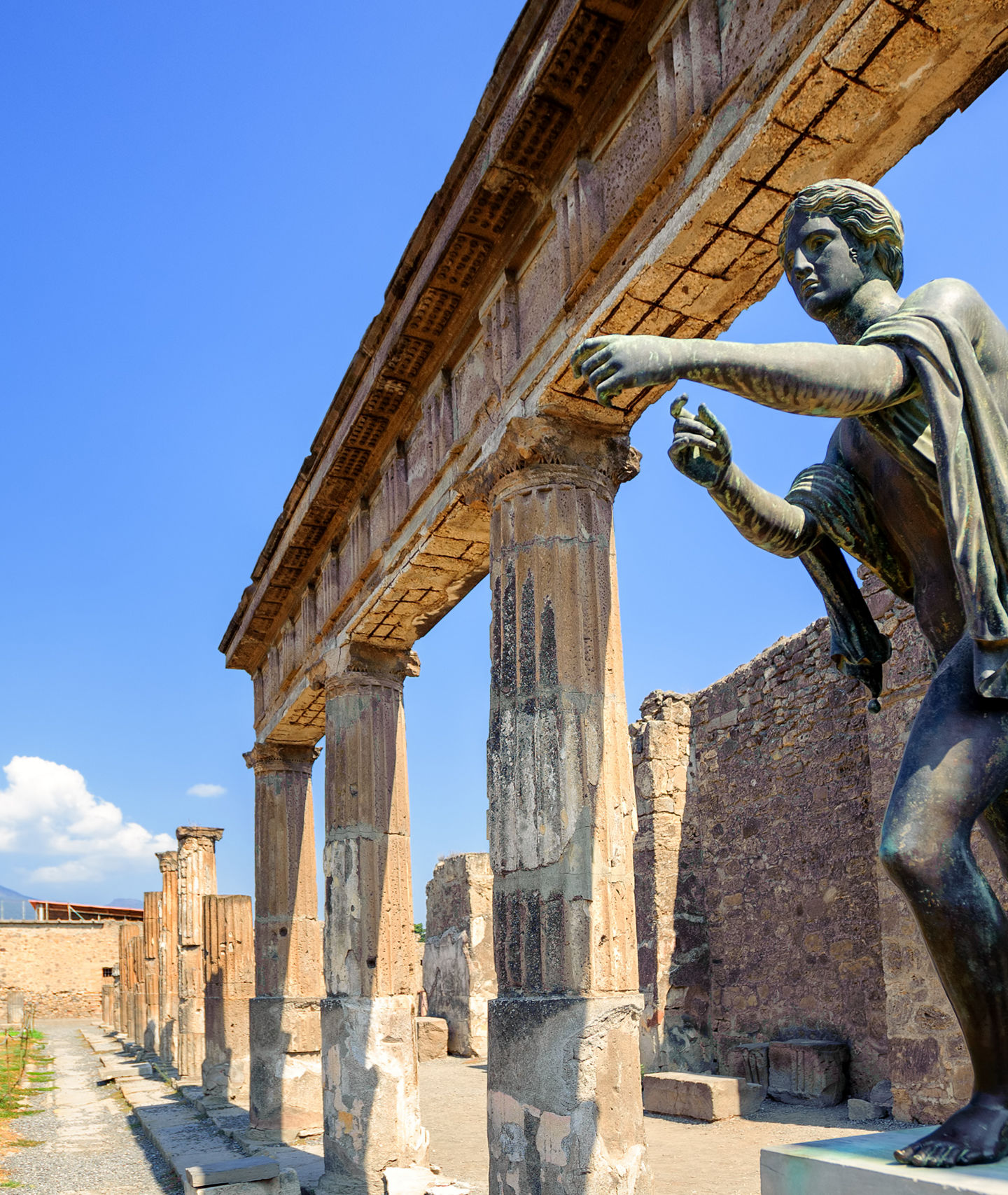 Ancient statue in Pompeii ruins under blue sky