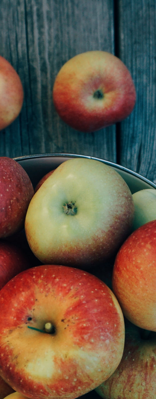 Fresh apples in a metal colander outdoors