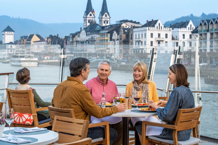 Group dining on riverside terrace at sunset