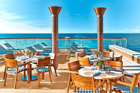 Oceanfront dining area with lounge chairs