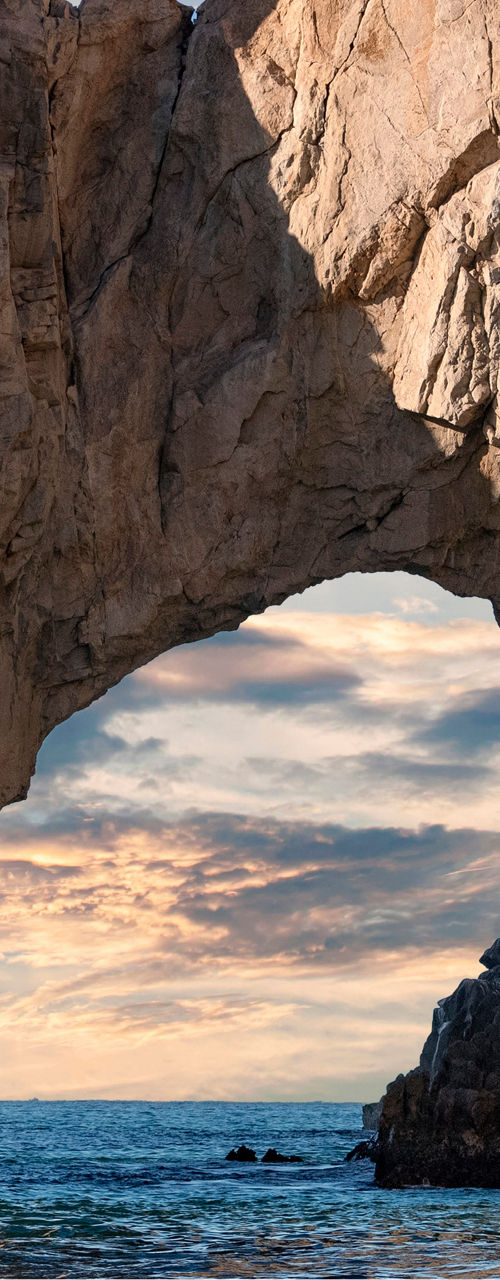 Natural rock arch at sunset over ocean
