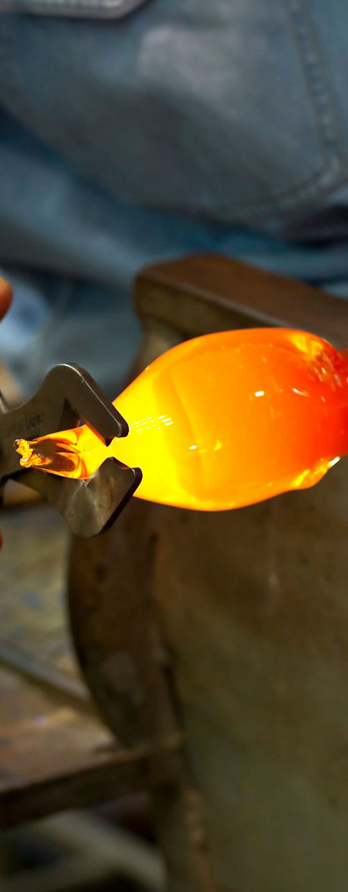 Glassblowing artisan shaping molten glass