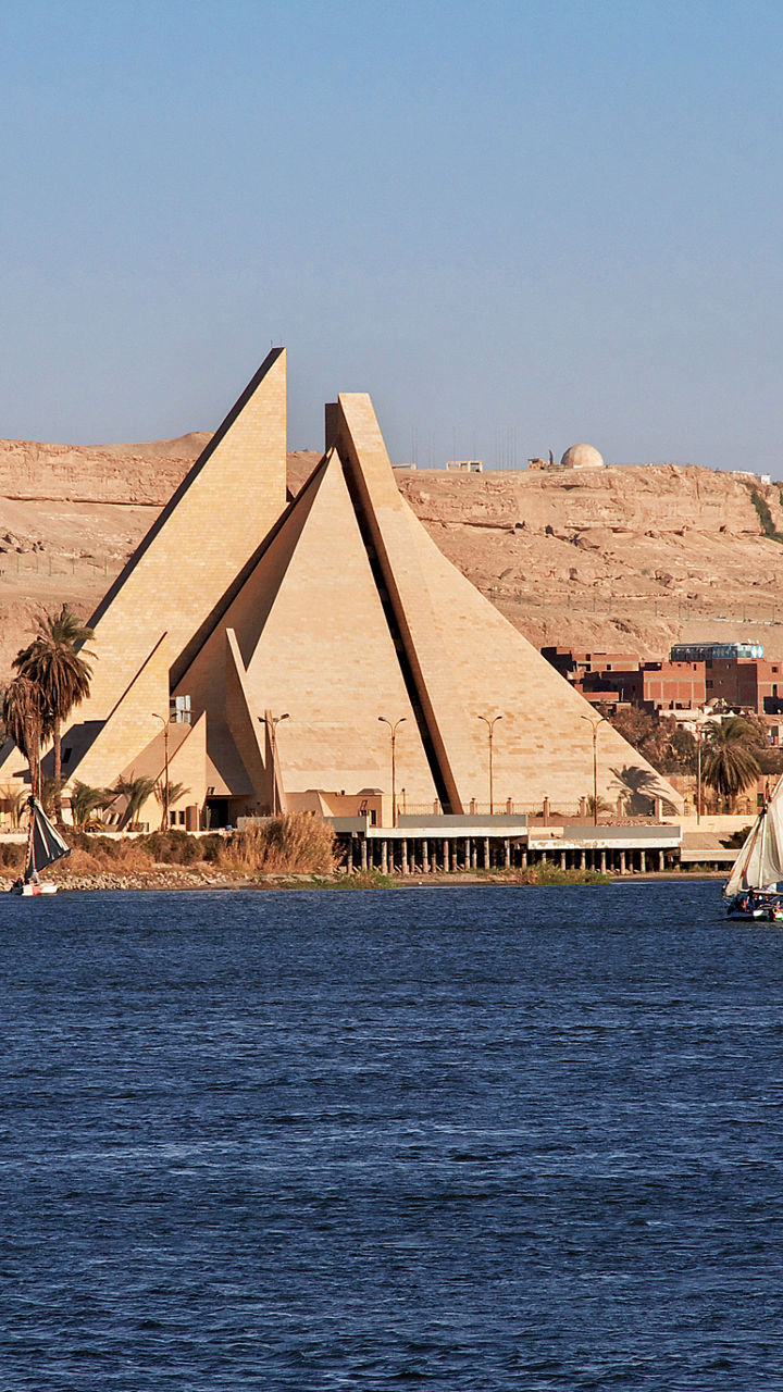 Modern riverside monument and sailboat at dusk