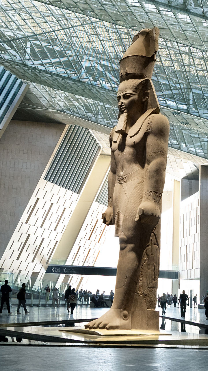Ancient Egyptian statue in modern museum atrium