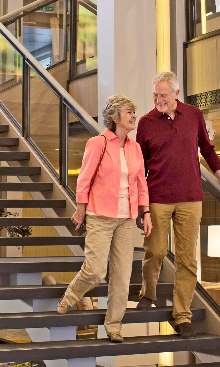 Senior couple walking down modern staircase
