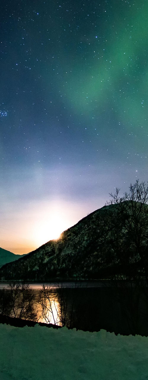 Northern lights over snowy mountain landscape