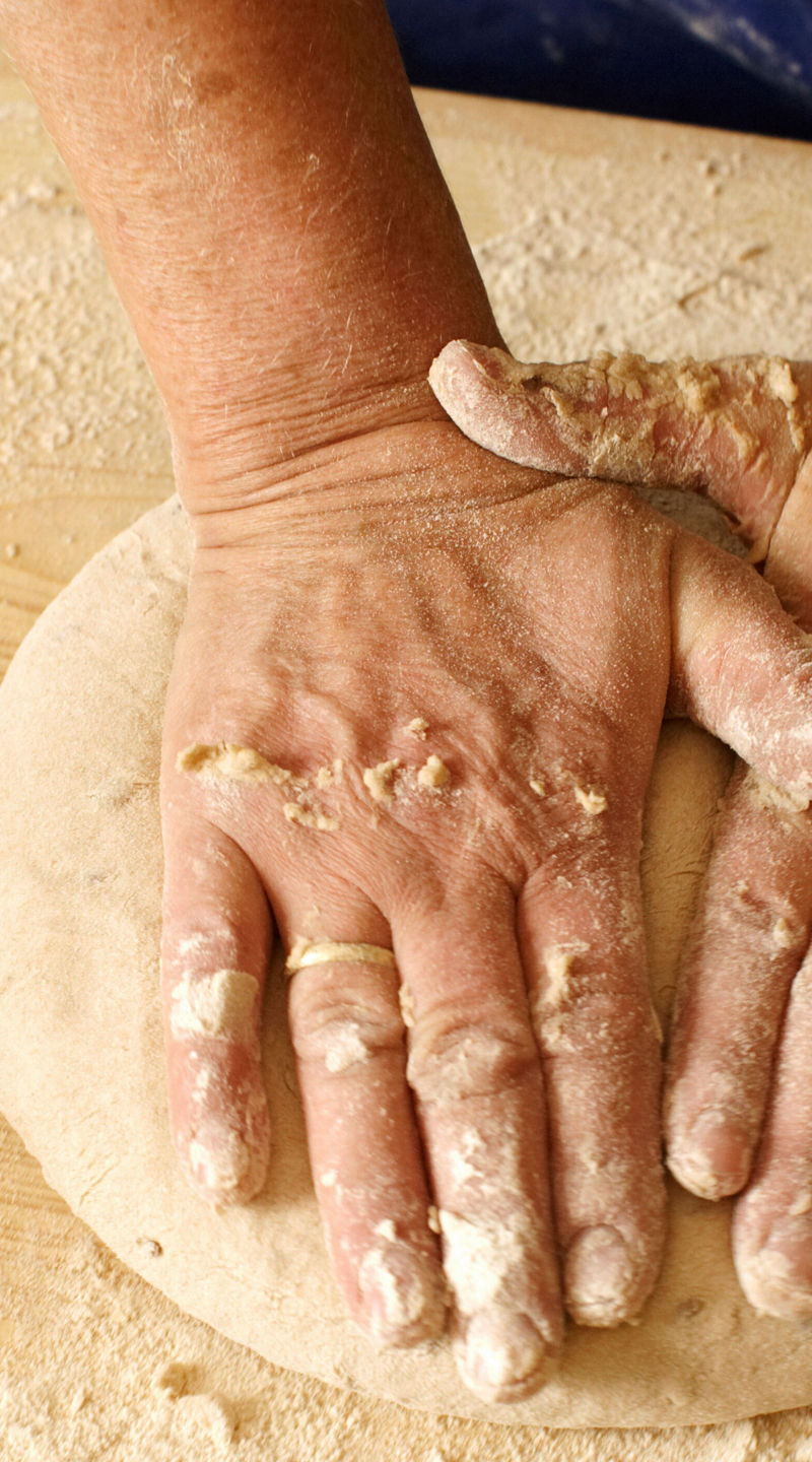 Hands kneading dough on wooden surface