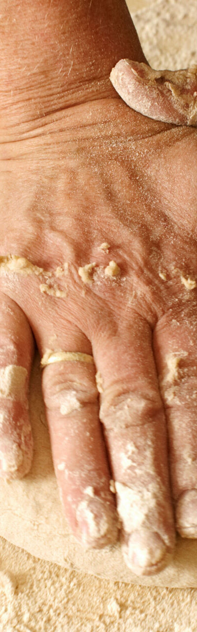 Hands kneading dough on wooden surface