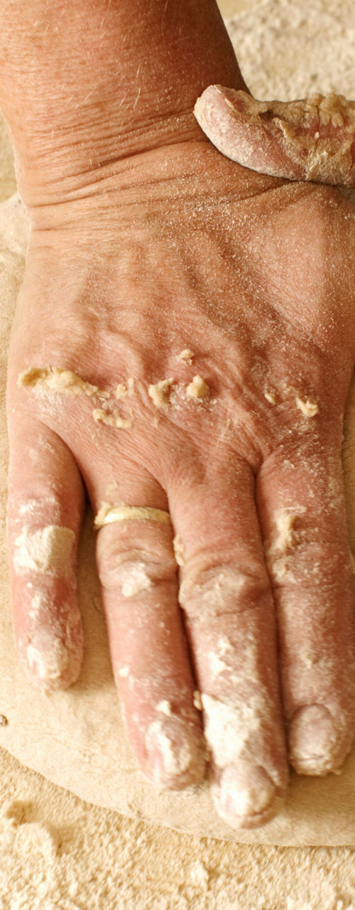 Hands kneading dough on wooden surface