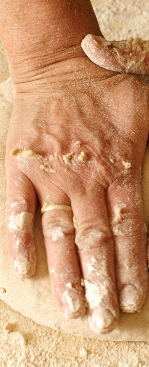 Hands kneading dough on wooden surface