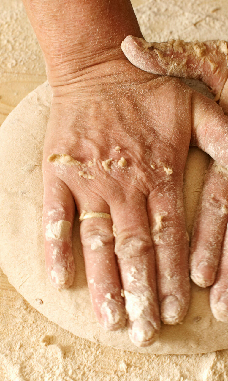 Hands kneading dough on wooden surface