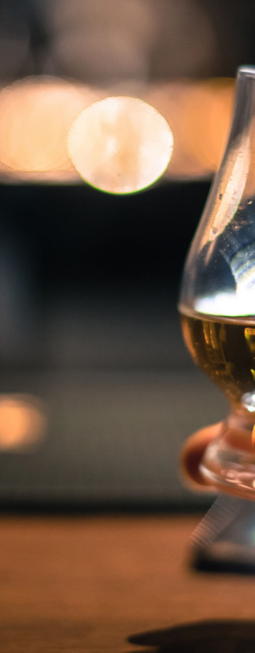 Hand holding whiskey glass in dim bar