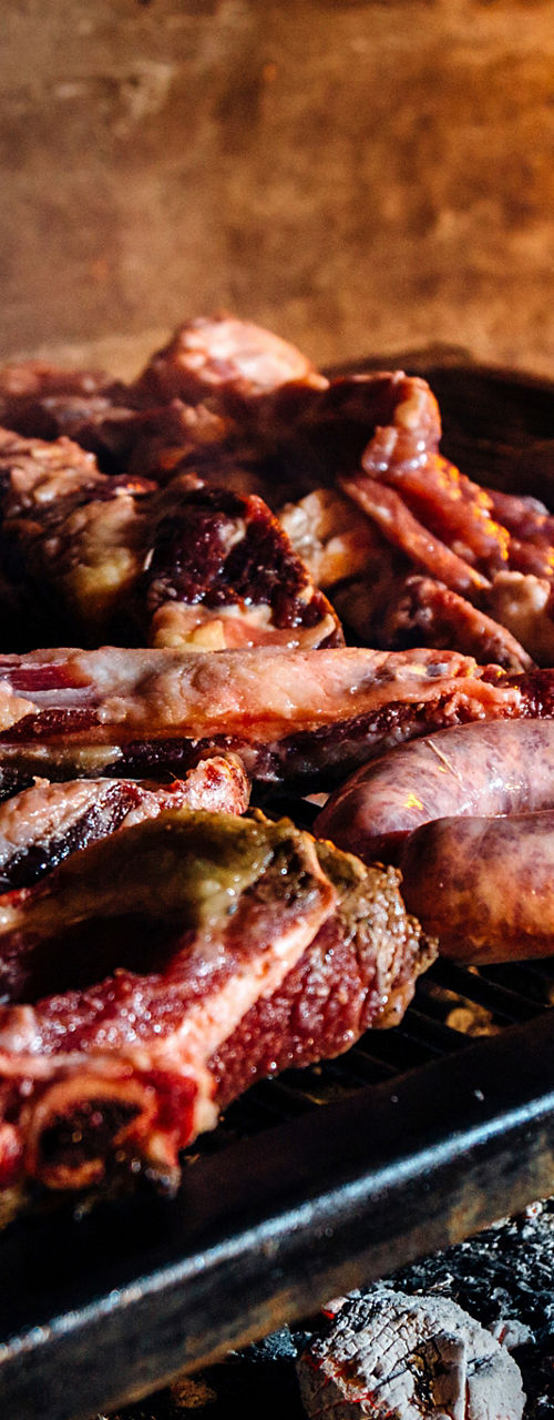 Assorted meats grilling over open wood fire