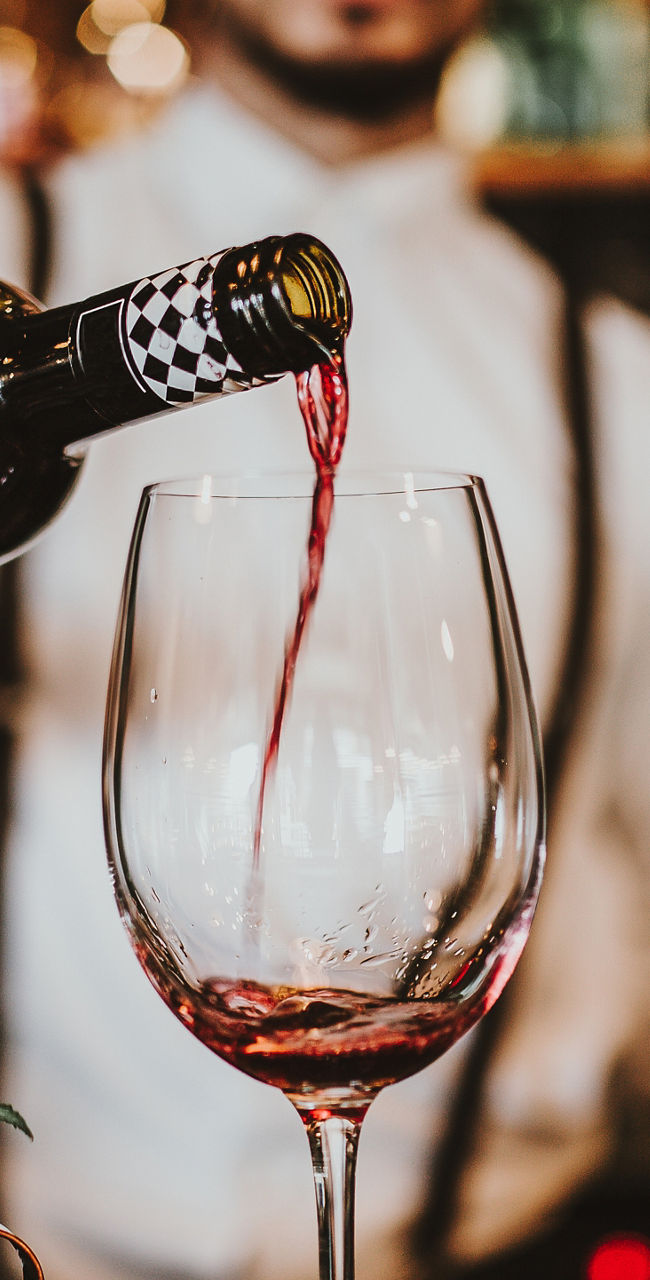 Bartender pouring red wine into glass