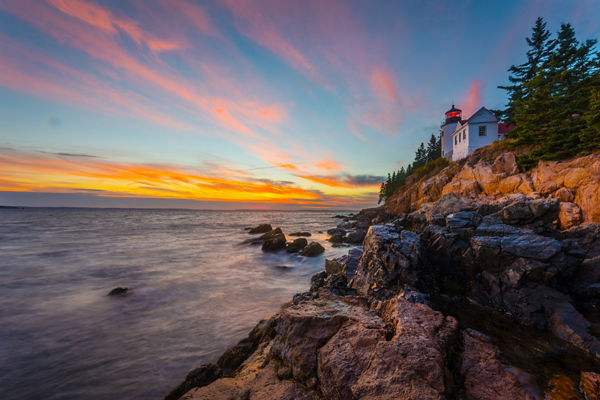 Coastal lighthouse at sunset with rocky shore