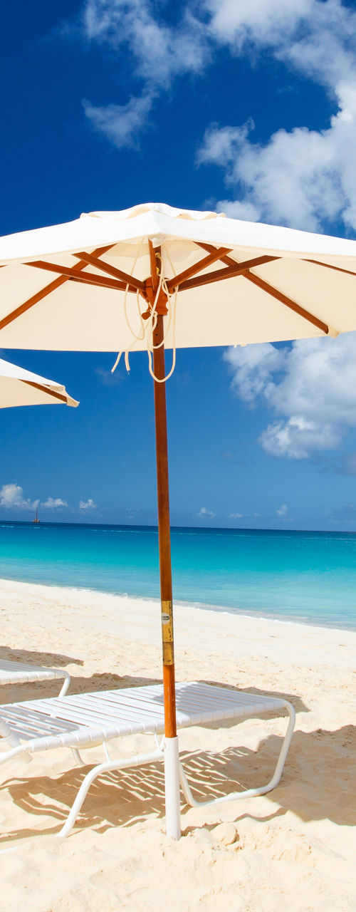 Empty lounge chairs under umbrellas on sandy beach