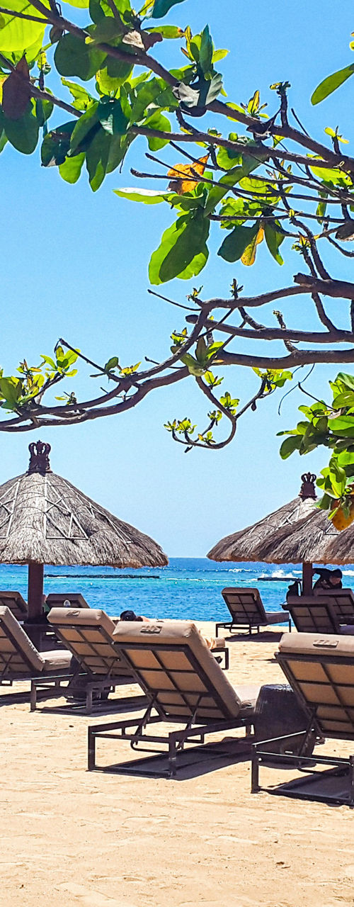 Beachfront lounge chairs under straw umbrellas