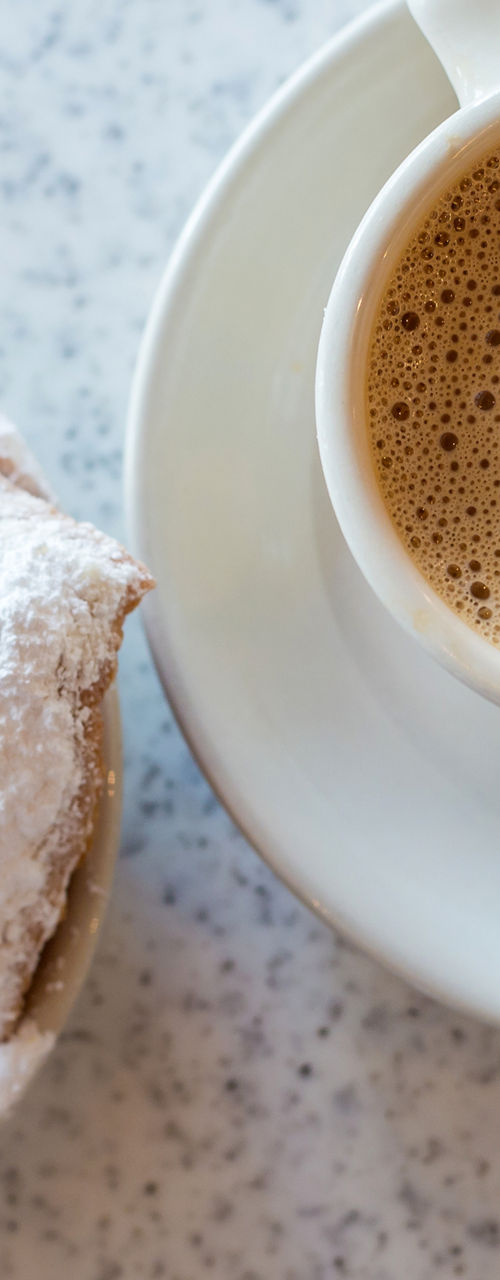 Coffee with powdered sugar pastries on table