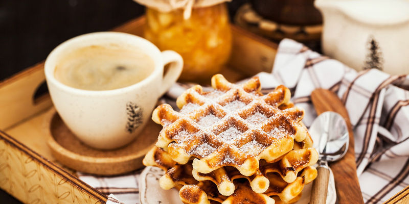 Fresh waffles with coffee on wooden tray