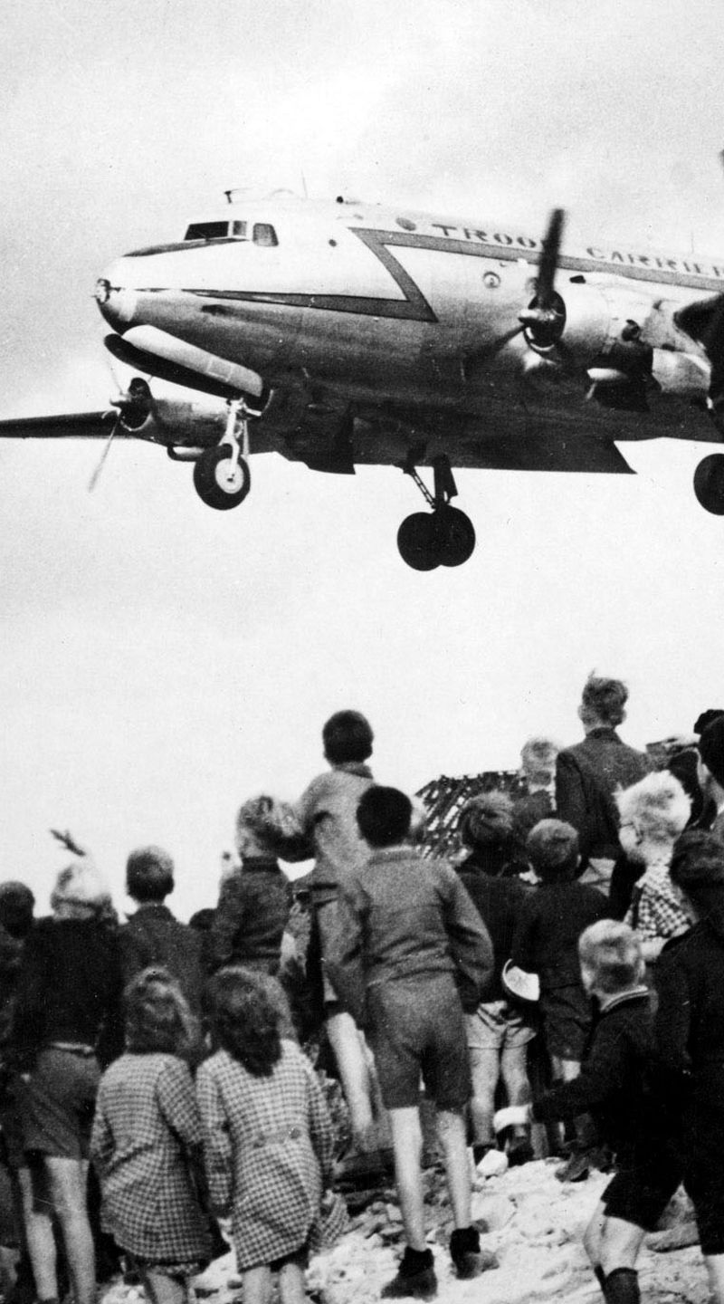Children watch airplane landing in urban area