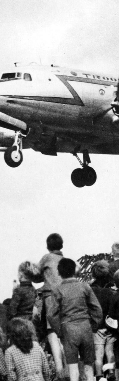 Children watch airplane landing in urban area