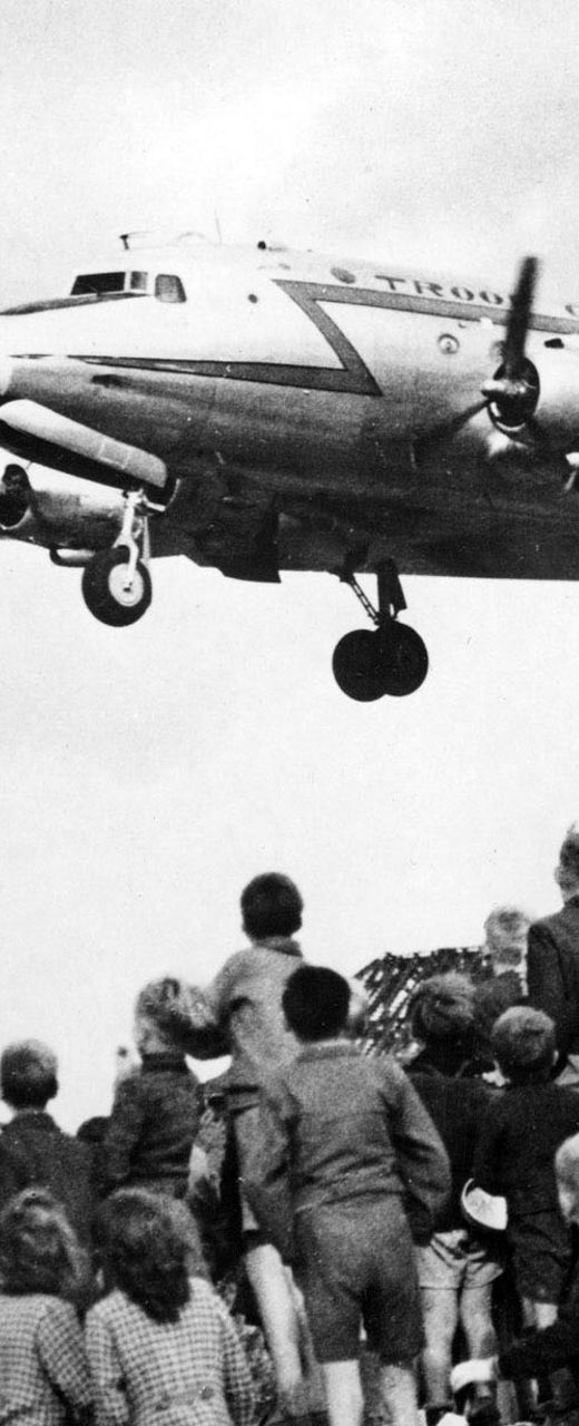 Children watch airplane landing in urban area