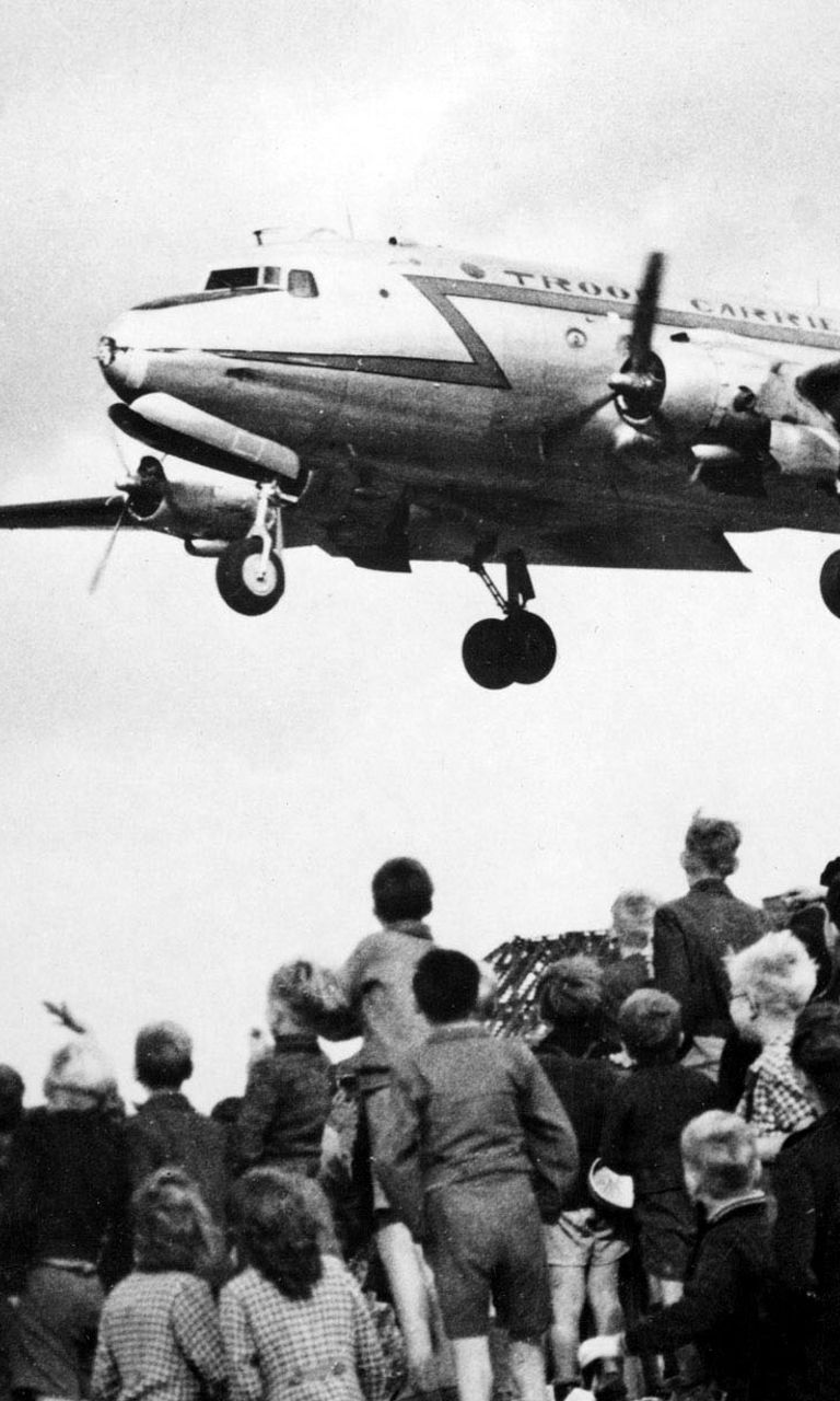 Children watch airplane landing in urban area
