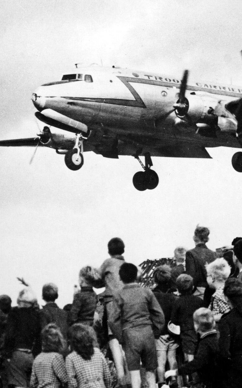 Children watch airplane landing in urban area