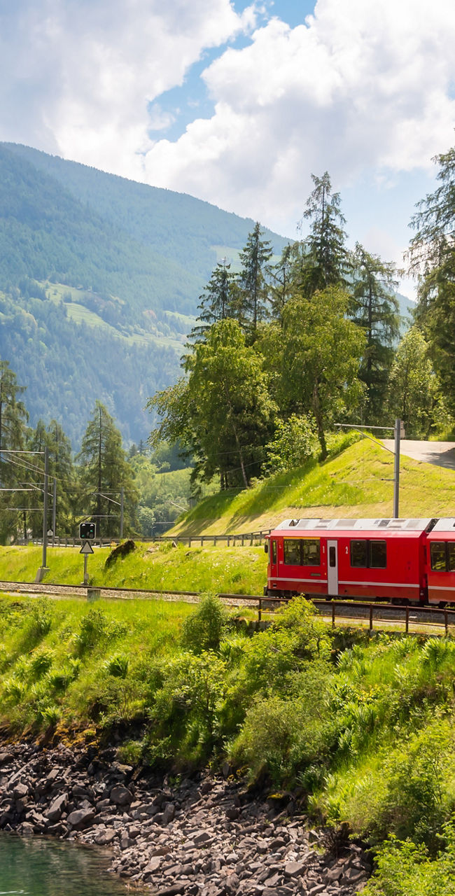 Red train traveling through scenic mountain landscape