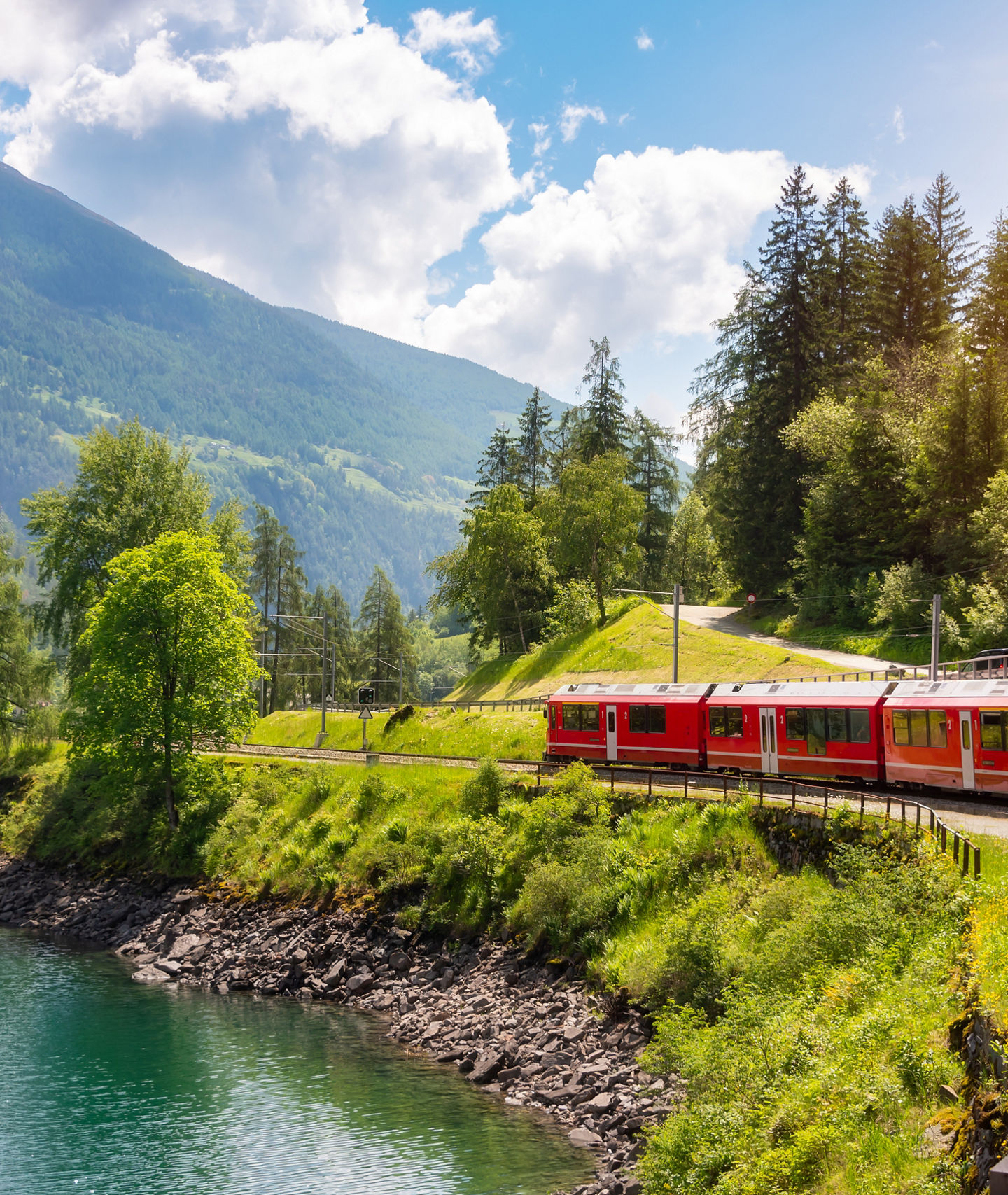 Red train traveling through scenic mountain landscape