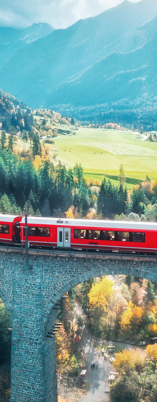Red train crossing scenic mountain viaduct