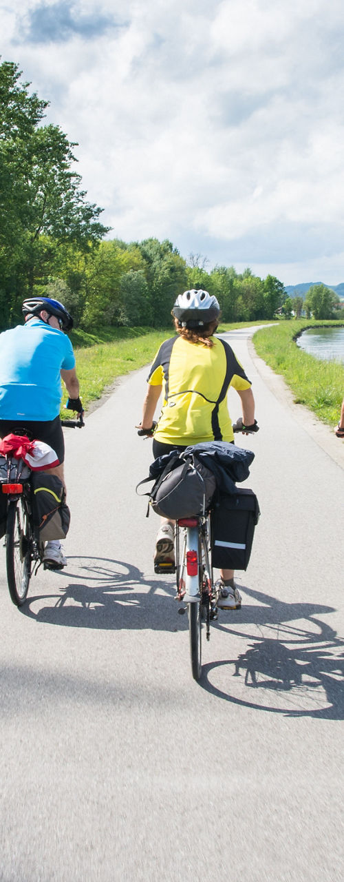 Group cycling along riverside trail