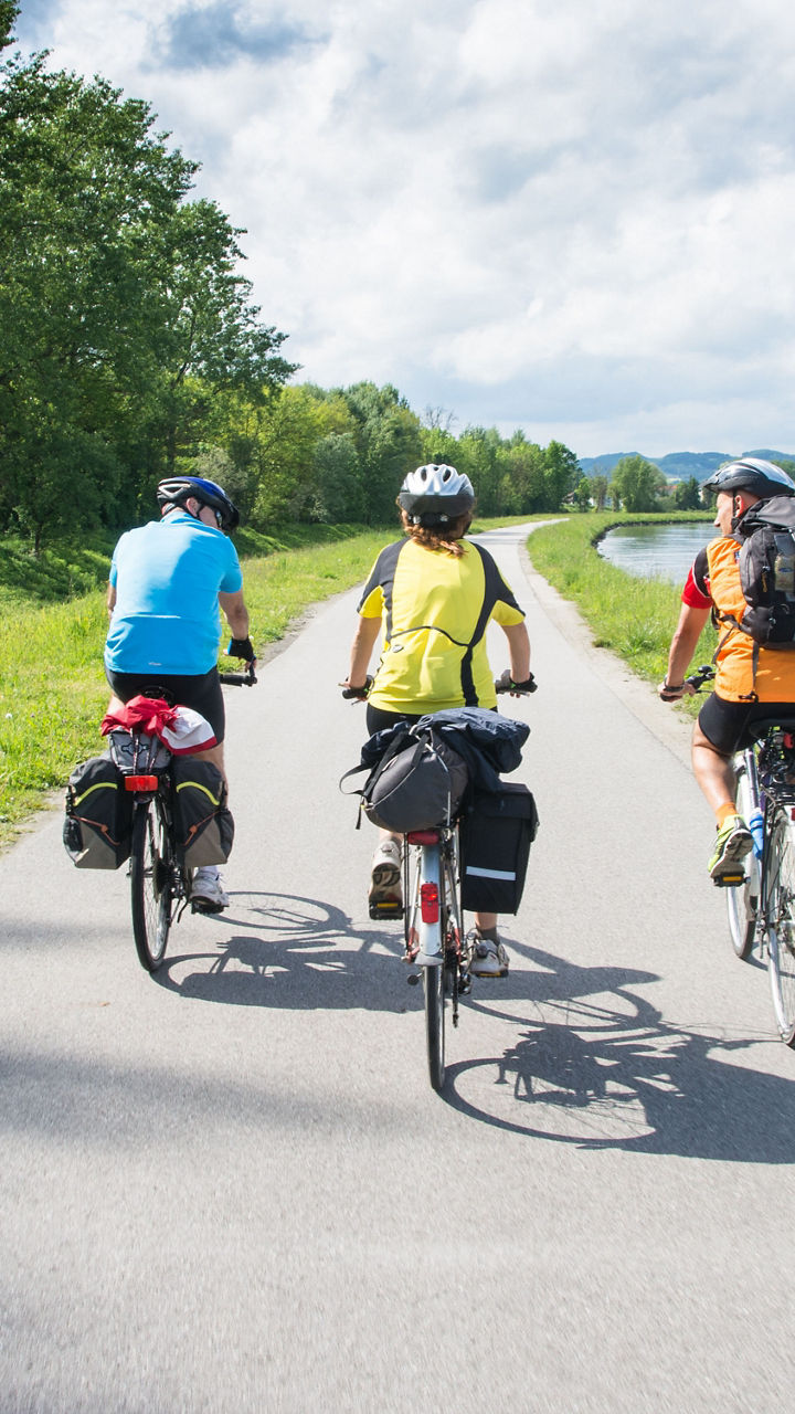 Group cycling along riverside trail