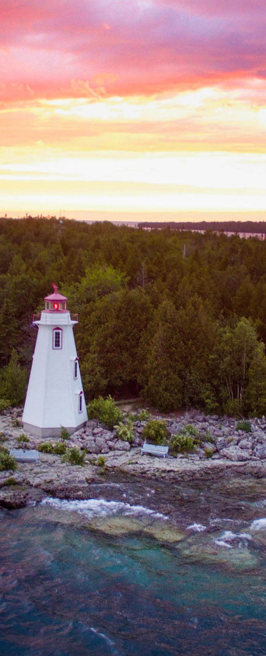 Scenic lighthouse at sunset on rocky island