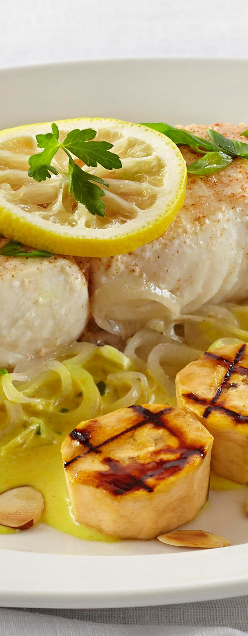 Grilled fish with lemon garnish and sides