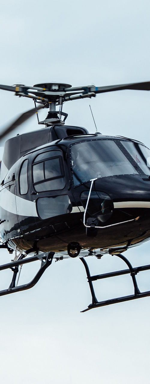 Black helicopter flying in cloudy sky