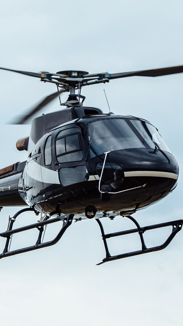 Black helicopter flying in cloudy sky