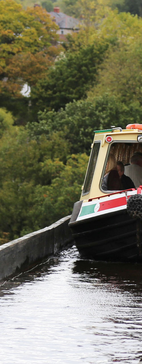 Canal boat crossing aqueduct in lush countryside