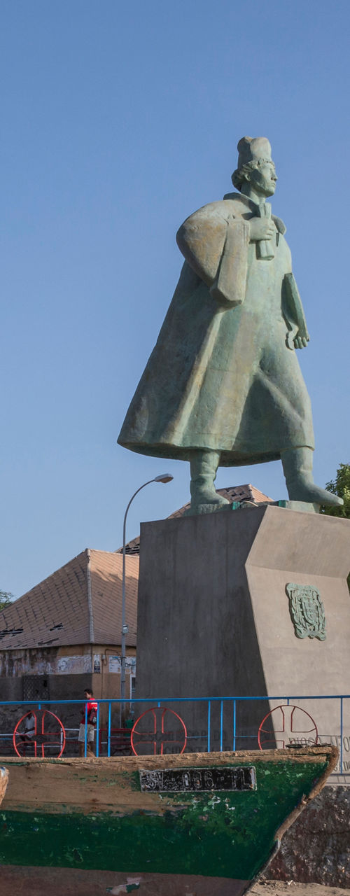 Statue in coastal town square with boats