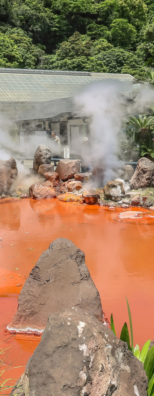 Steaming Red Hot Spring Pond in Lush Green Landscape