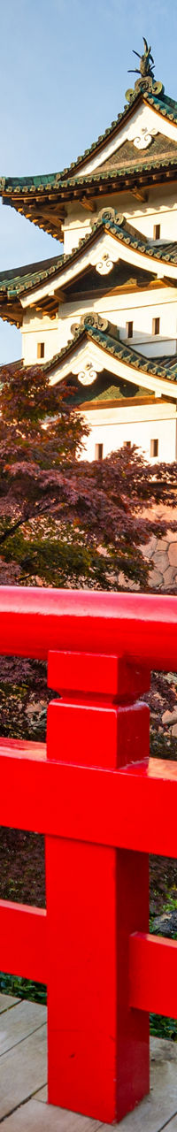 Traditional Japanese castle behind vibrant red bridge