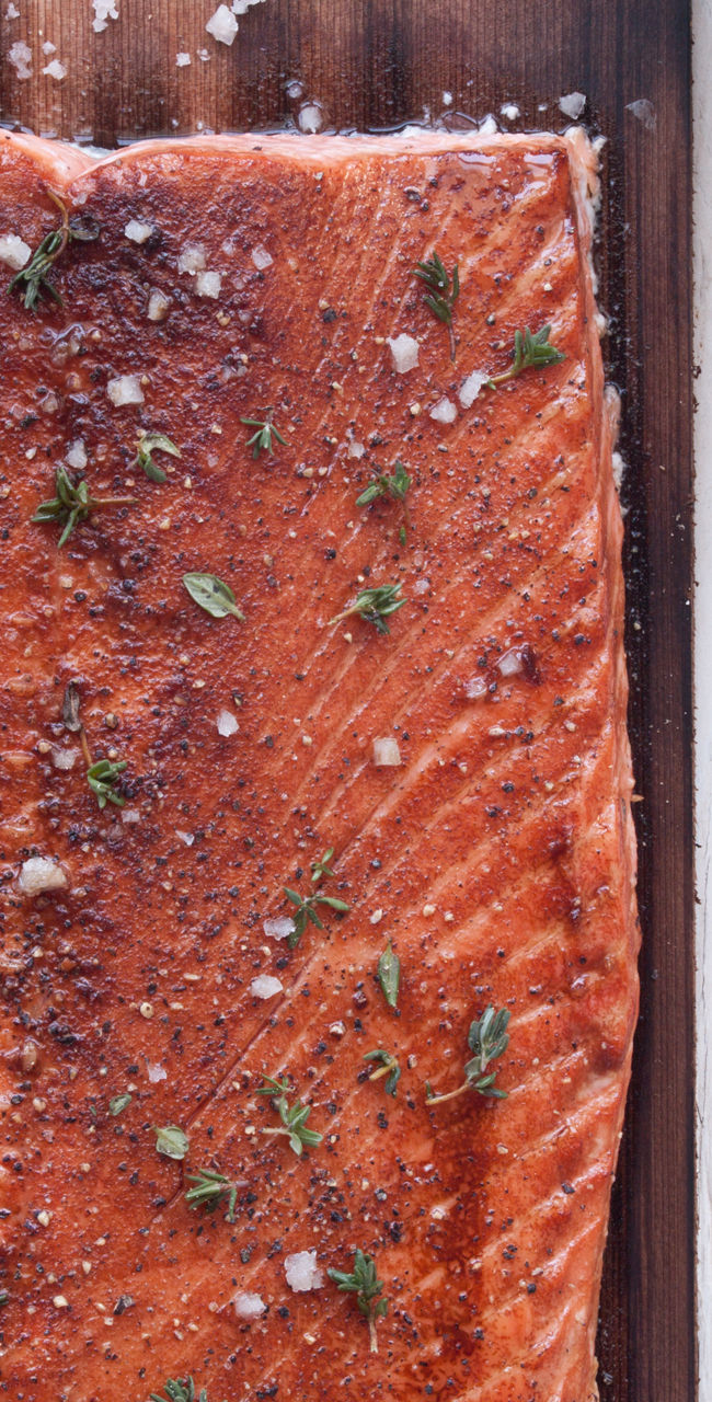 Grilled salmon on wooden plank with seasoning