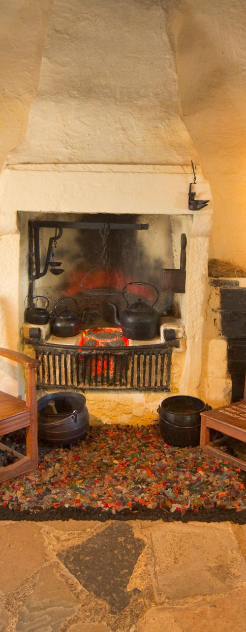 Rustic cottage interior with fireplace and spinning wheel