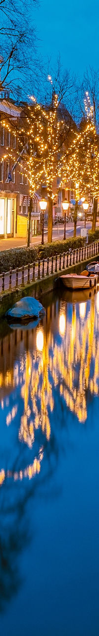 Illuminated canal in Amsterdam at dusk
